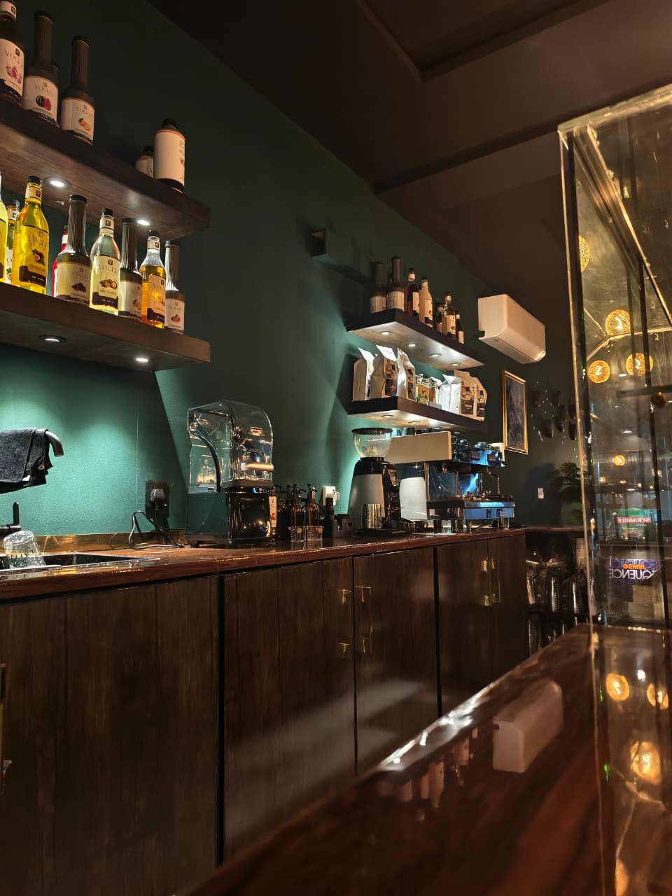 Caffio's coffee bar with espresso equipment, syrups, wooden cabinetry, and Forest green walls