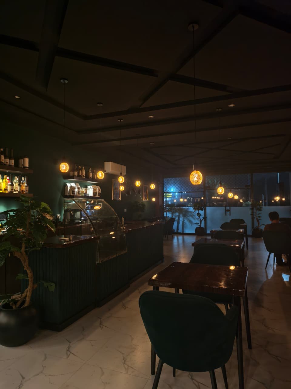 A wide view across Caffio's counter, seating, pendant lights, and front windows